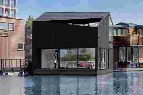 This angular timber home in Amsterdam’s sustainable floating village uses the jetty’s power grid for clean energy!